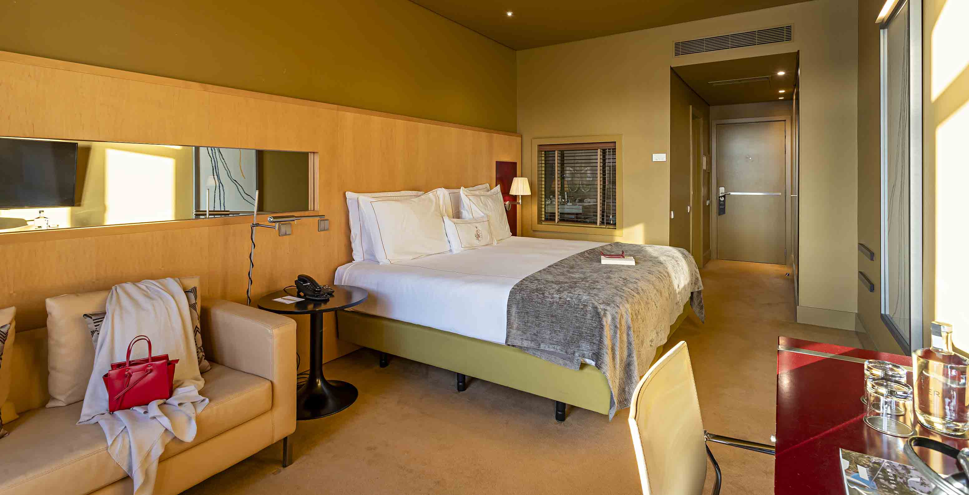 O Executive Superior do Pestana Palácio do Freixo tem uma cama de casal, um sofá e uma secretária vermelha