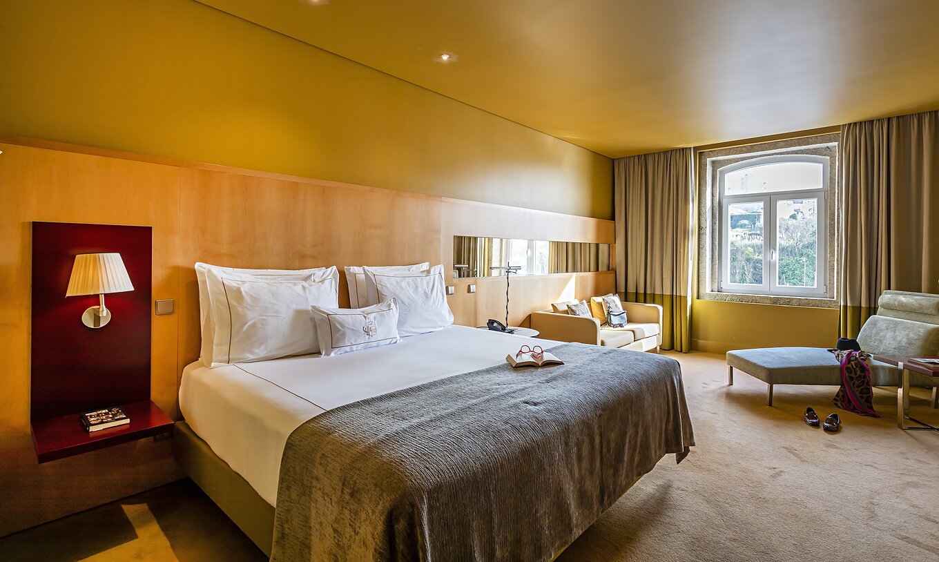 O Superior do Pestana Palácio do Freixo tem uma cama de casal com colcha cinzenta e uma janela com vista