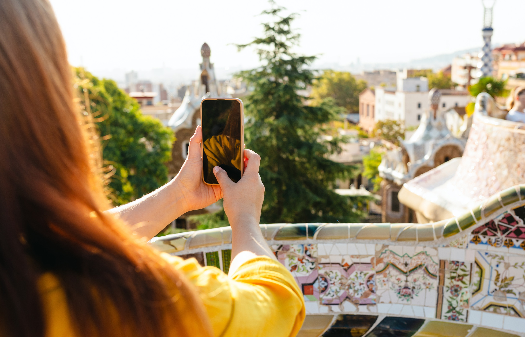 Pessoa a fotografar com o seu telemóvel a vista da cidade de Barcelona no famoso Parque Güell