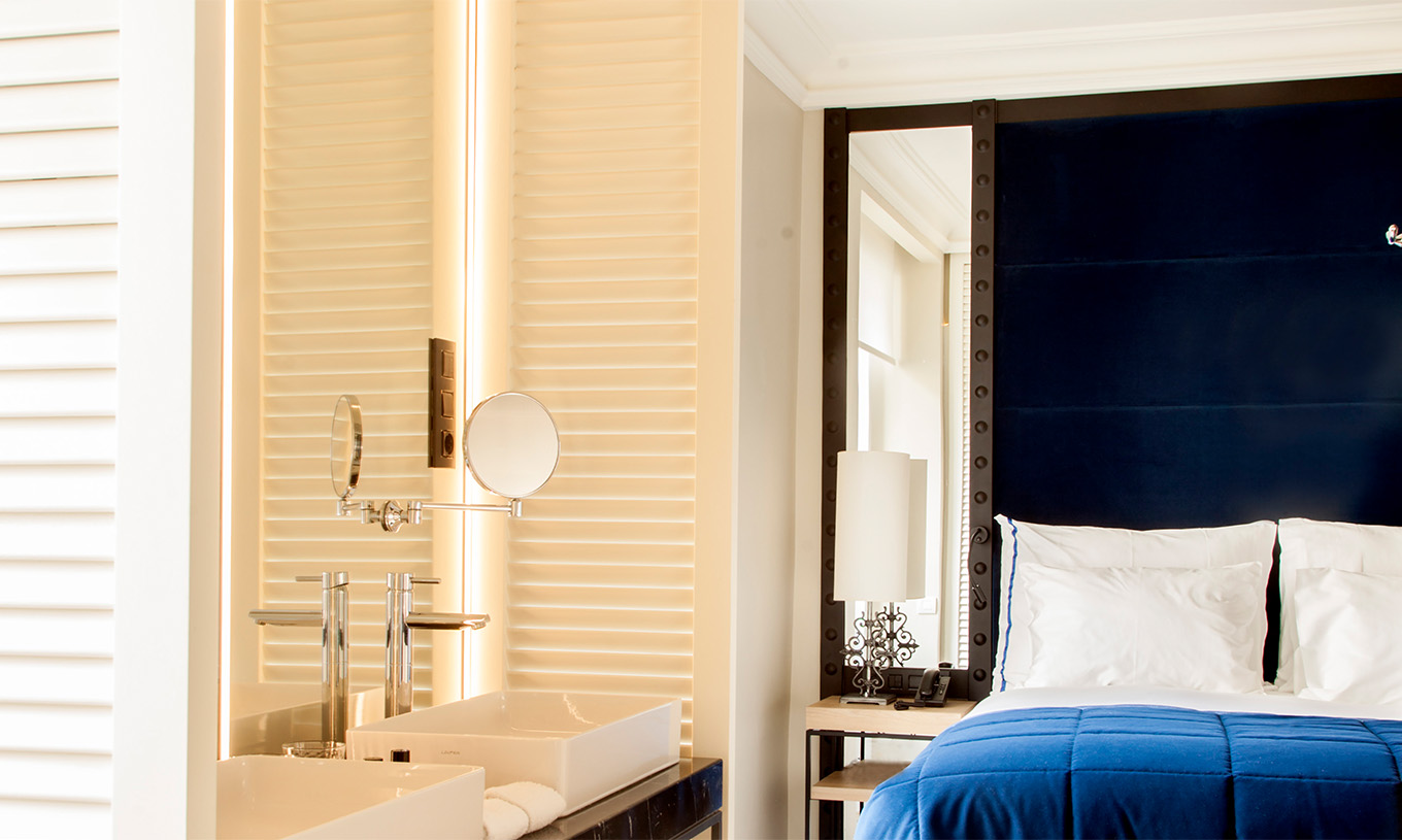 O Quarto Superior do Pestana Plaza Mayor Madrid tem uma cama de casal com cabeceira azul com espelho e um lavatório