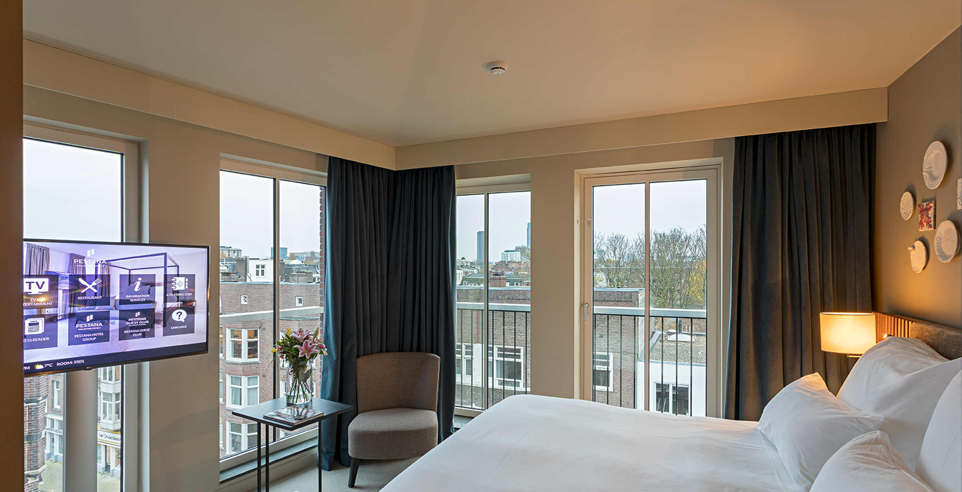 O quarto Estúdio Clássico do Pestana Amsterdam Riverside tem uma cama de casal, um candeeiro e janelas com vista para a rua