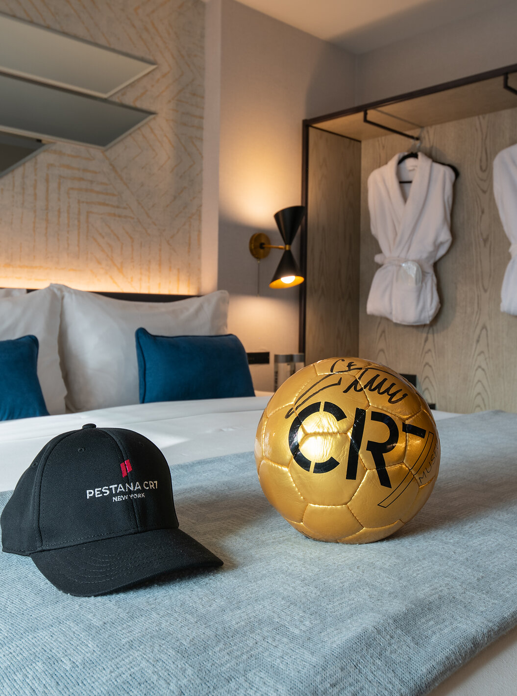 O Deluxe King Room ADA do Pestana CR7 Times Square tem uma cama de casal com uma bola e um chapéu do CR7