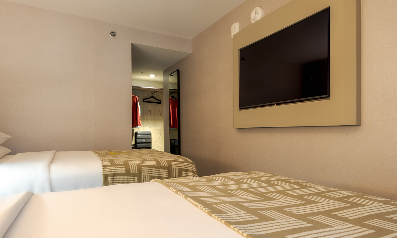 O Comfort Double do Pestana CR7 Times Square tem duas camas com uma colcha com o número sete e uma televisão