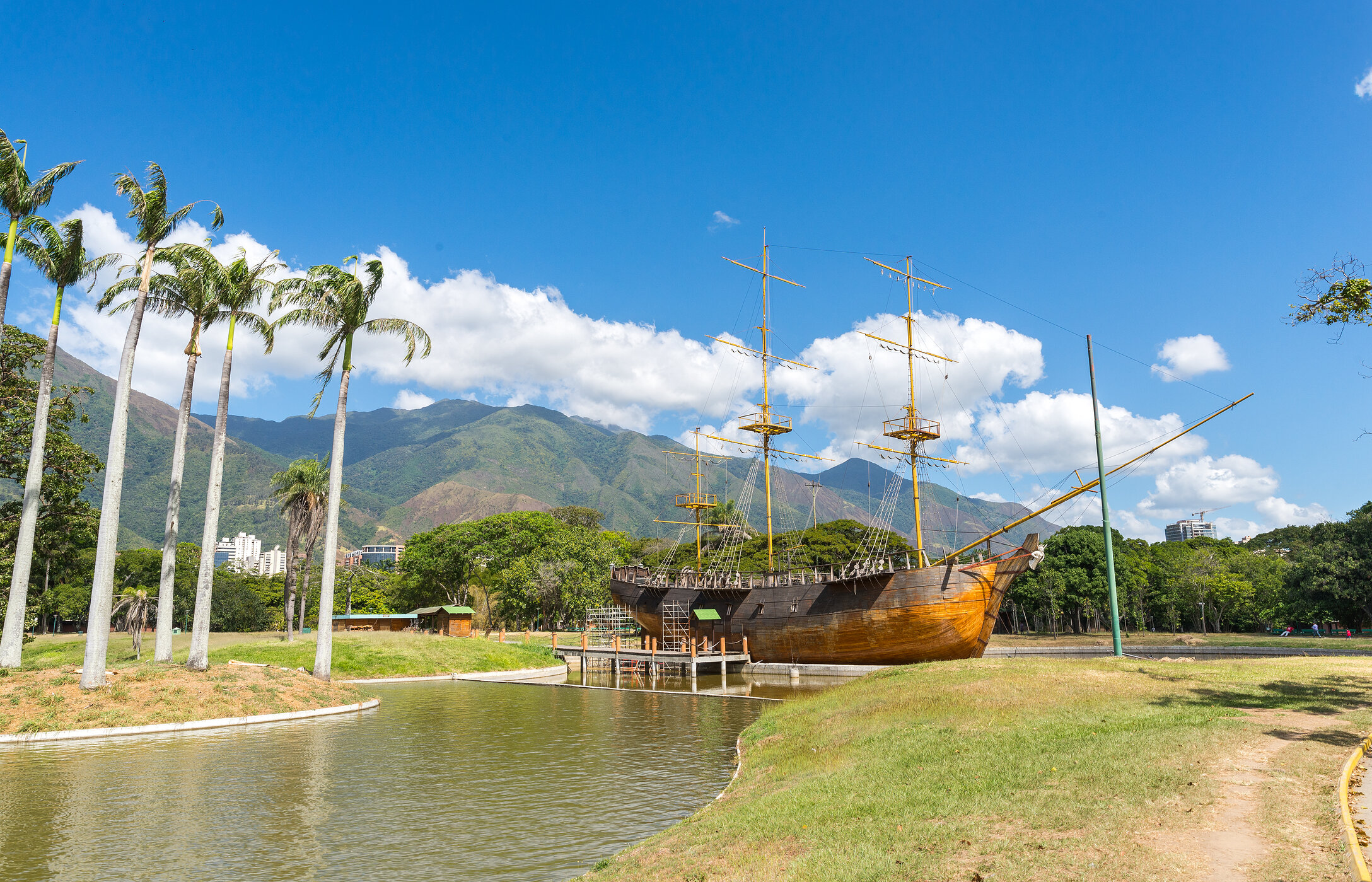 Parque del Este, situado em Caracas, com um lago e um navio histórico ancorado, com montanhas e vegetação no fundo