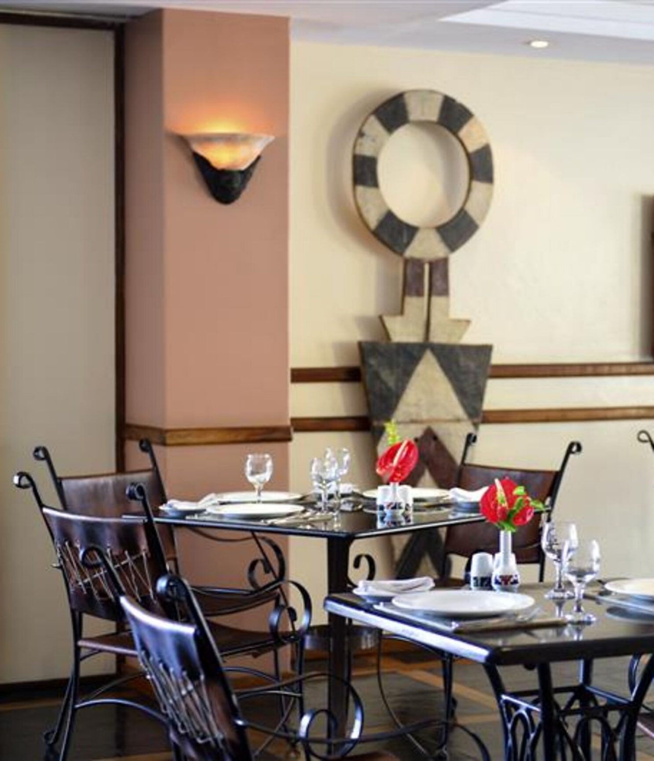Das Restaurant Piazza del Campo im 4-Sterne-Hotel in Maputo hat Tische und schwarze Stühle sowie Kunst an den Wänden