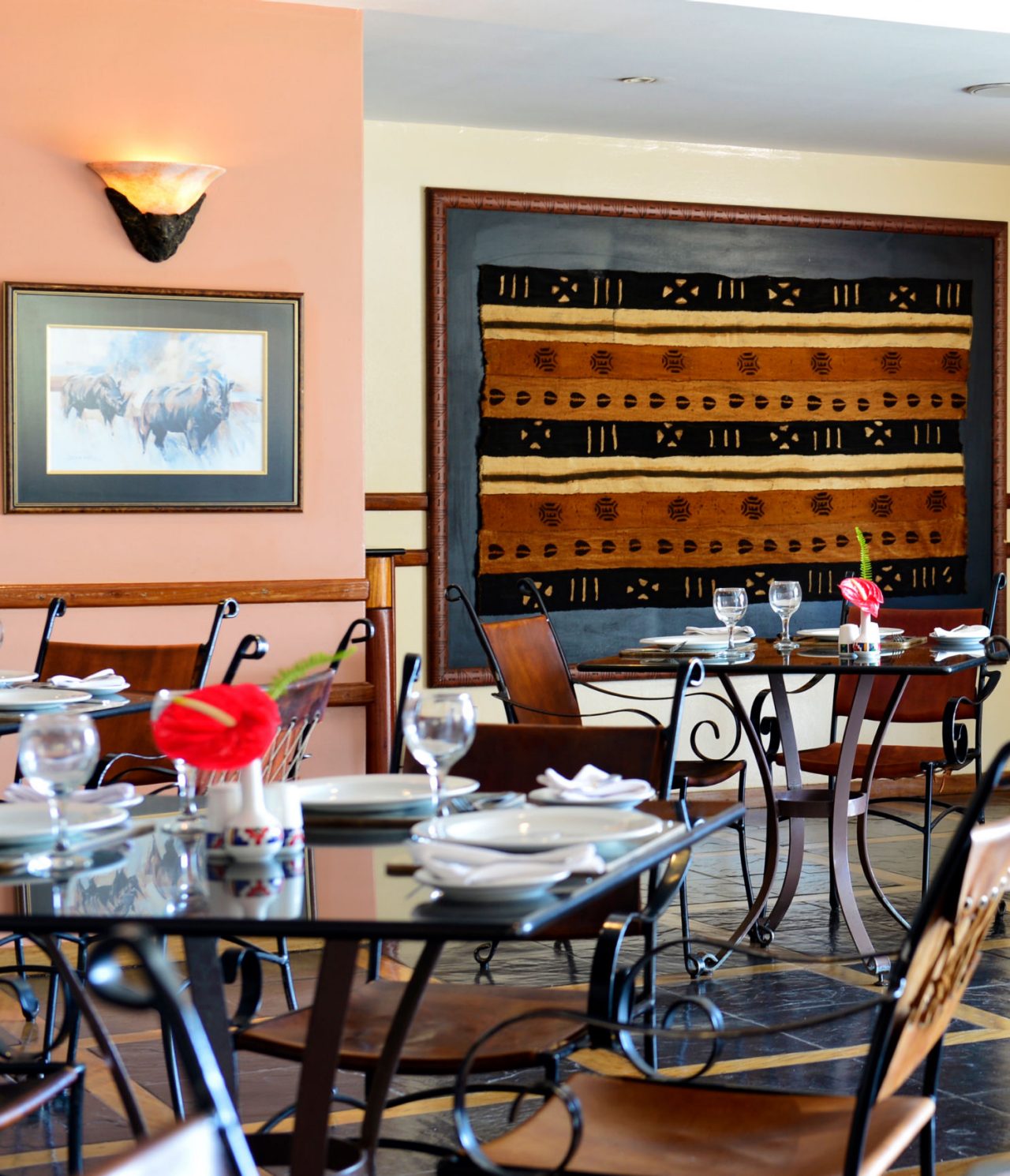 Das Restaurant Monomotapa im 4-Sterne-Hotel in Maputo hat mehrere Tische mit einer roten Blume und Stühlen