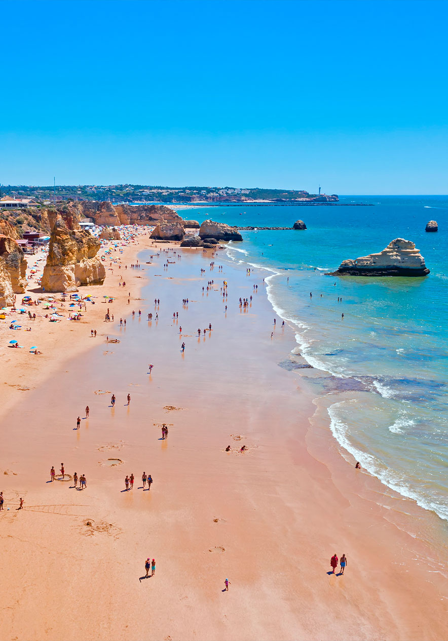 Besuchen Sie den Praia da Rocha mit vielen Felsen am goldenen Strand, der auf das blaue Wasser des Algarve trifft