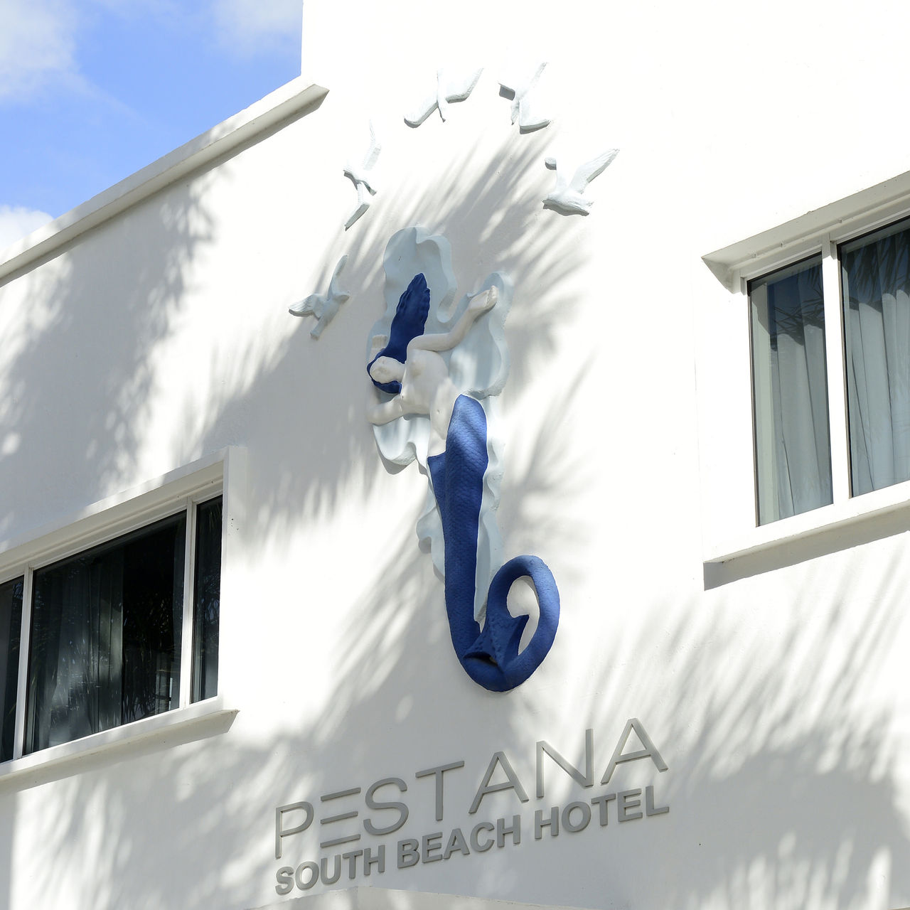 Facade of Pestana Miami South Beach hotel, featuring a prominent sculpture of a mermaid and the number 1831