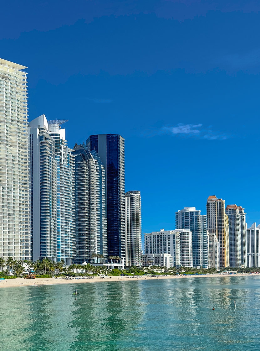 Vista sobre la costa de Miami Beach con modernos rascacielos junto al mar, playas de arena clara y agua azul cristalina