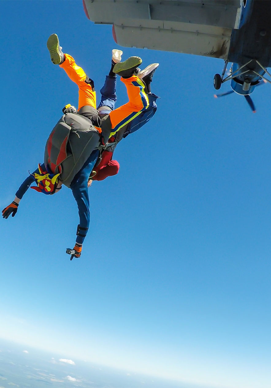Un garçon fait du parachutisme dans l'Algarve, en chute libre avec les bras ouverts, avec un ciel bleu tout autour