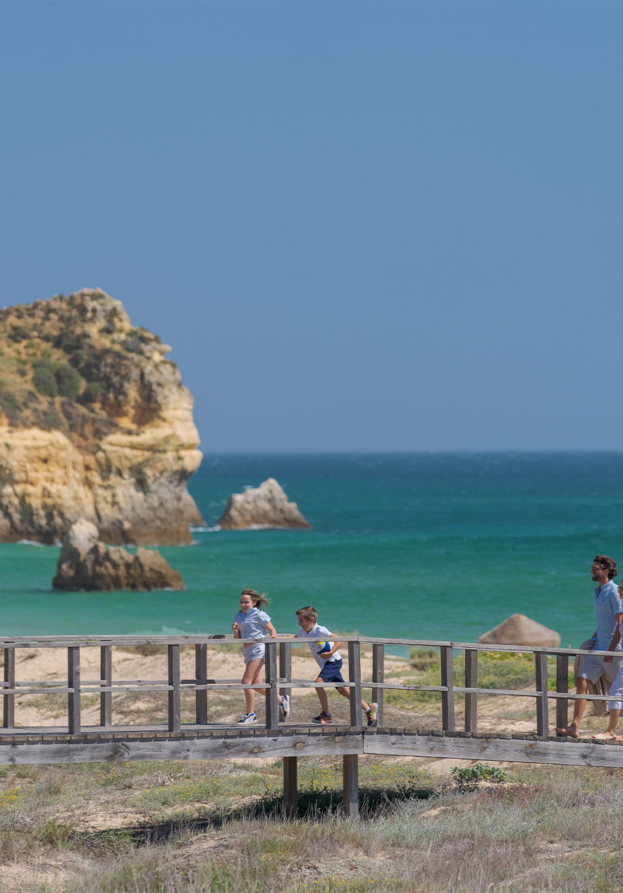 Passerelles en bois des plages d'Alvor, avec la mer en arrière-plan et deux enfants courant avec leurs parents