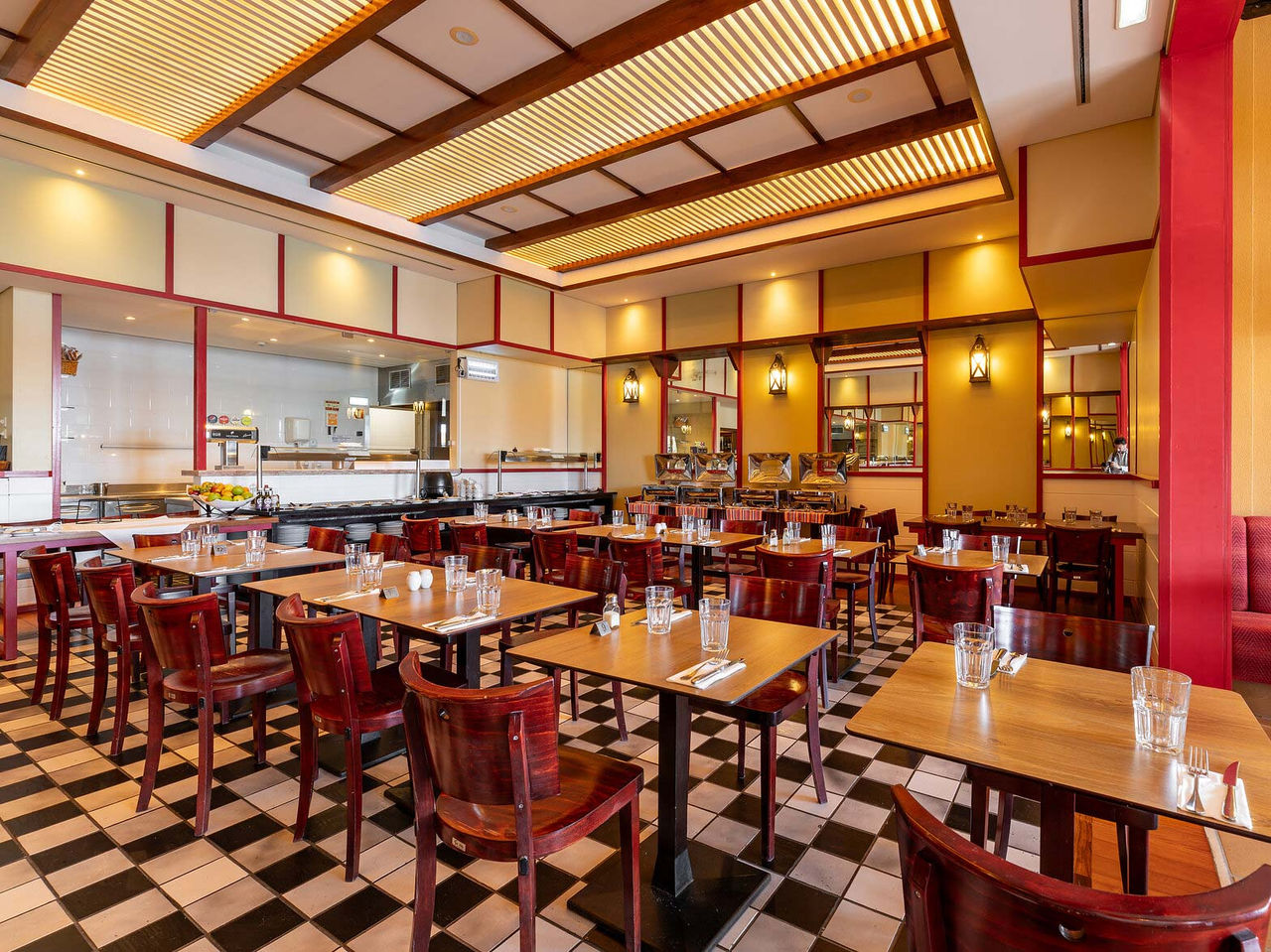 Le restaurant Luigi du Resort 5 étoiles à Porto Santo a un sol en carreaux noirs et blancs et des chaises sombres.
