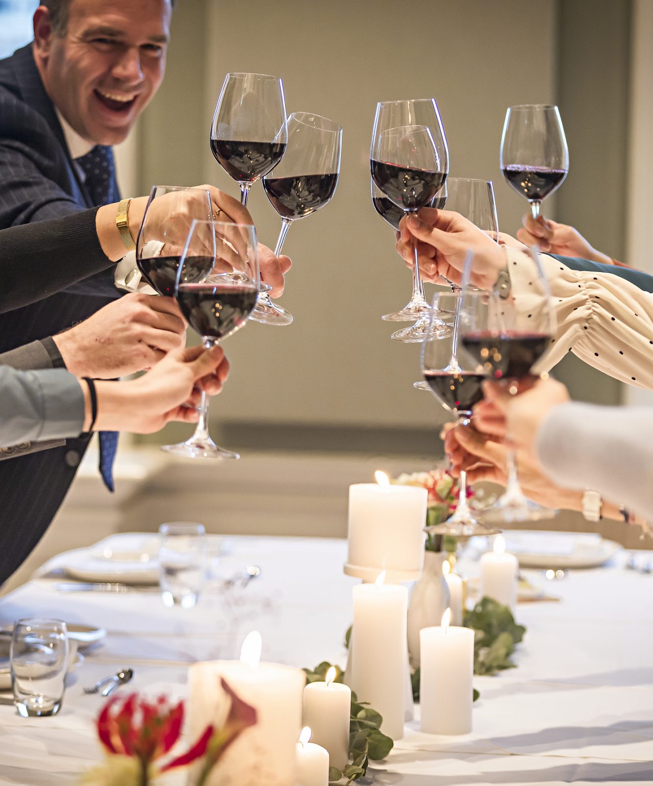 Gasten proosten met glazen rode wijn op een bruiloft met elegante decoratie bij Pestana Hotel Group