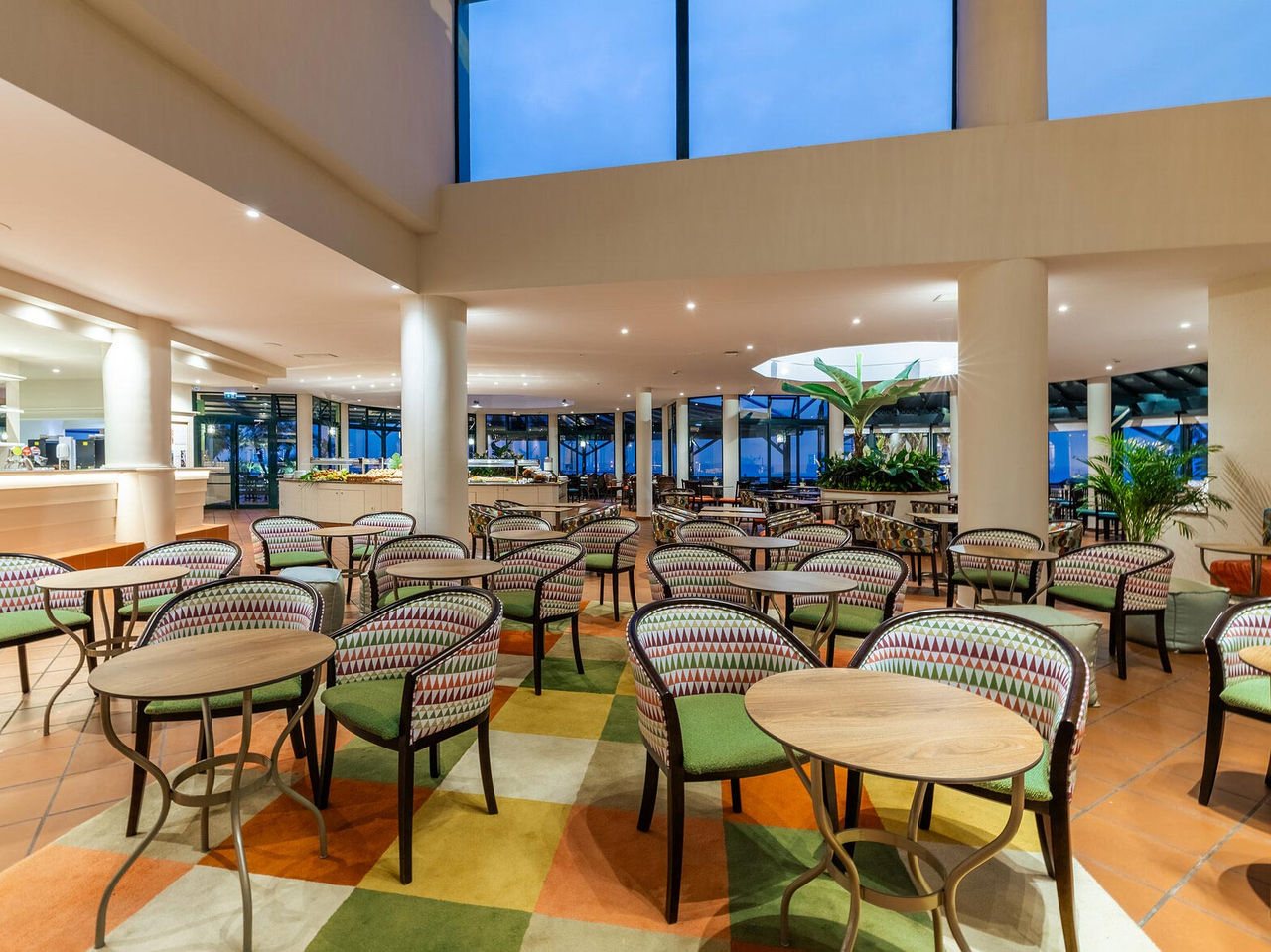 De Arlequim bar van het 5-sterrenhotel in Funchal, Madeira heeft stoelen met ronde tafels en een geruite vloerbedekking