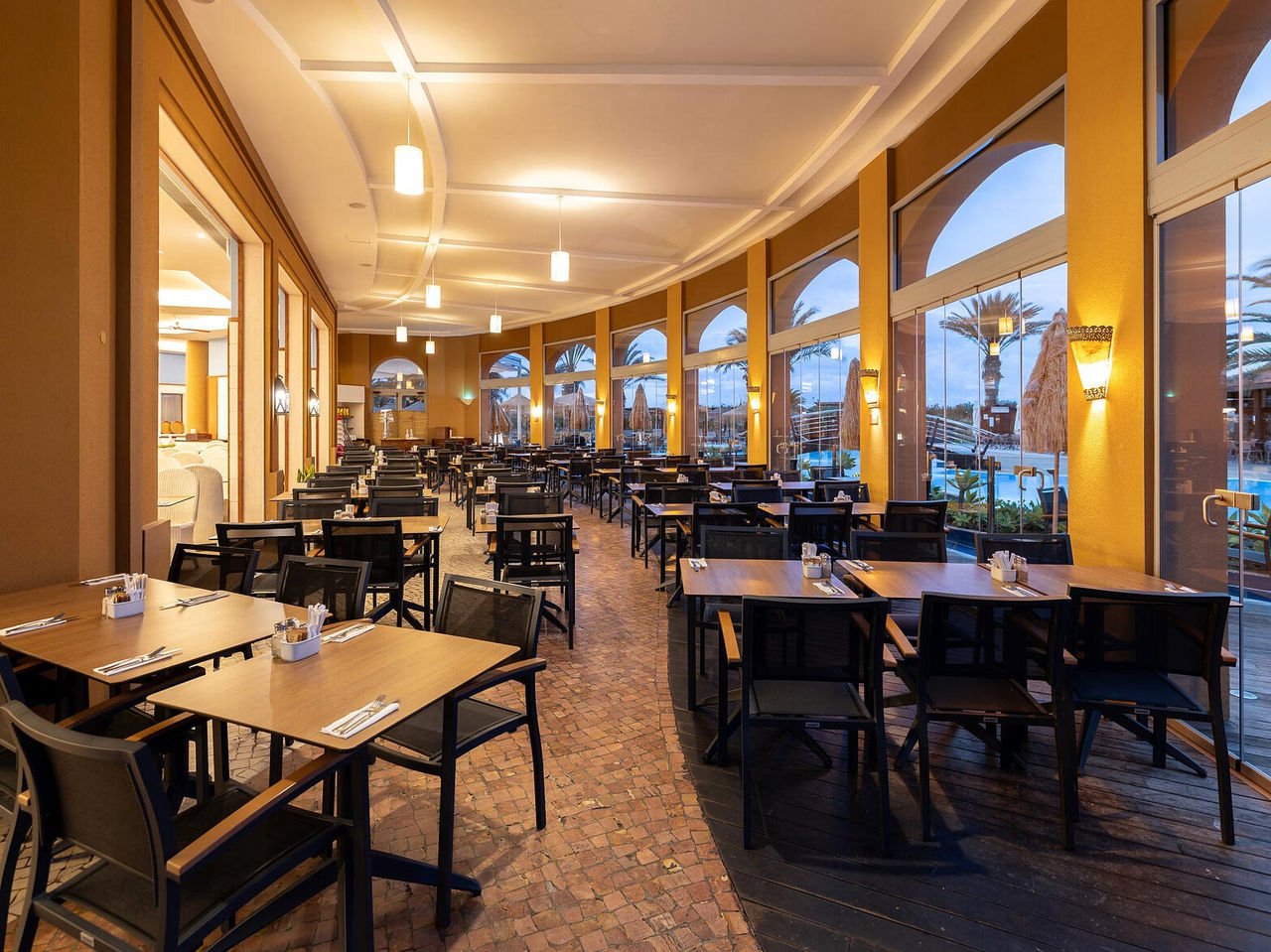 Restaurant Marés van het 5-sterrenresort op Porto Santo heeft een ruime ruimte met gele muren en groene stoelen.