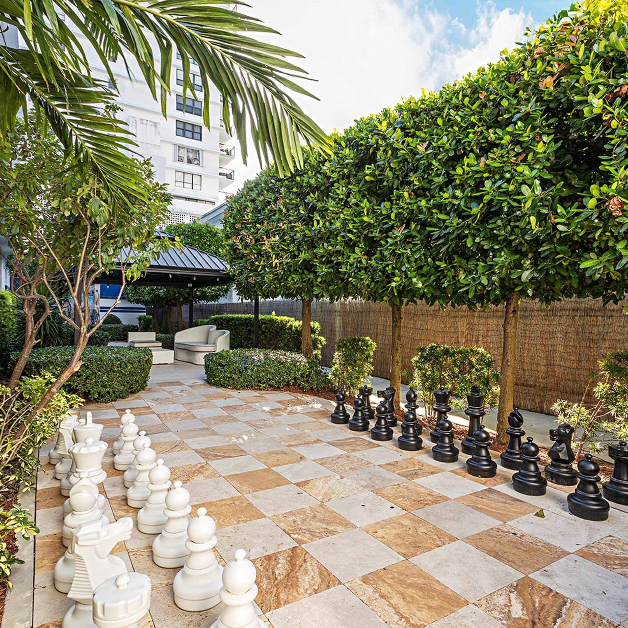 Pestana South Beach Miami, Boetiekhotel in Miami met schaakbord in een tuin met palmbomen en zitgedeelte
