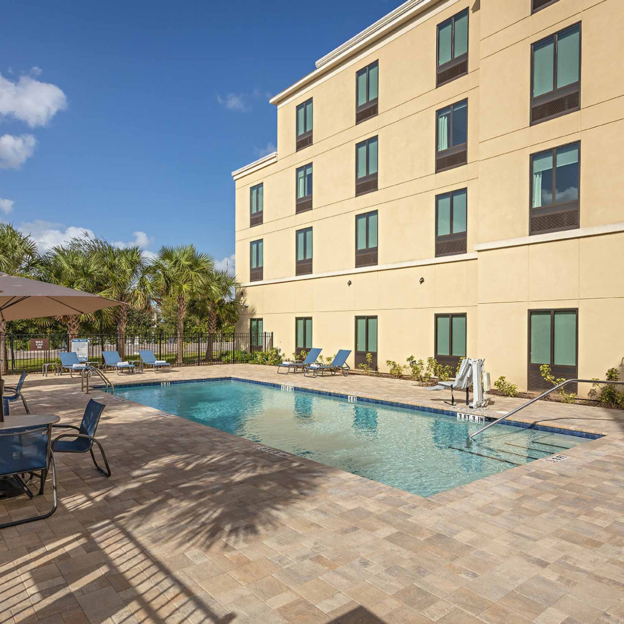 Pestana Orlando Suites Lake Buena Vista, Hotel in Orlando, VS met buitenzwembad naast ligstoelen en palmbomen