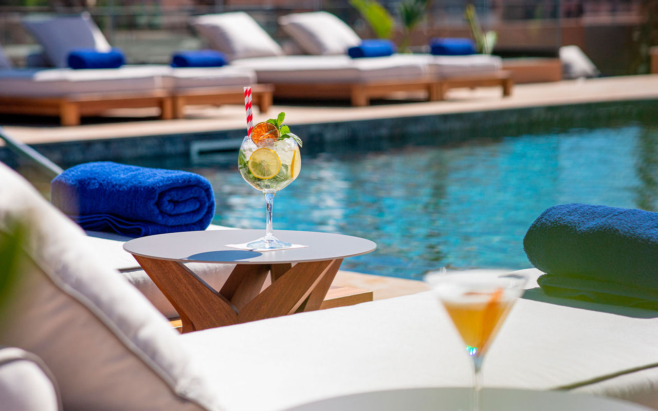 Het merk Pestana CR7 Lifestyle Hotels met cocktails naast een zwembad en ligbedden met blauwe handdoeken