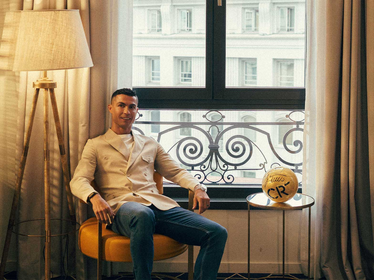 Het merk Pestana CR7 Lifestyle Hotels met een man in beige jasje naast een gesigneerde voetbal bij het raam