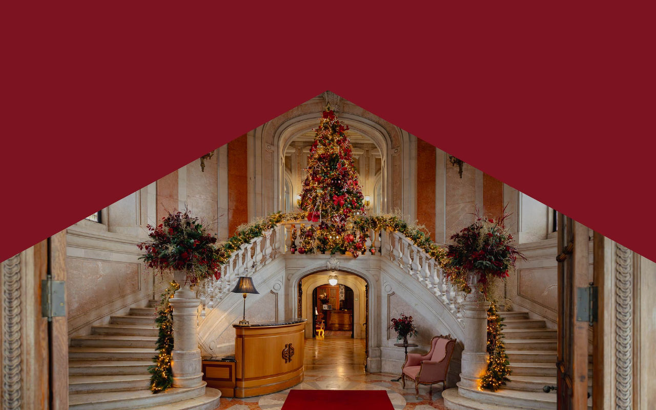 Feestelijk versierde hotellobby met dubbele marmeren trap, grote kerstboom en warme kerstverlichting
