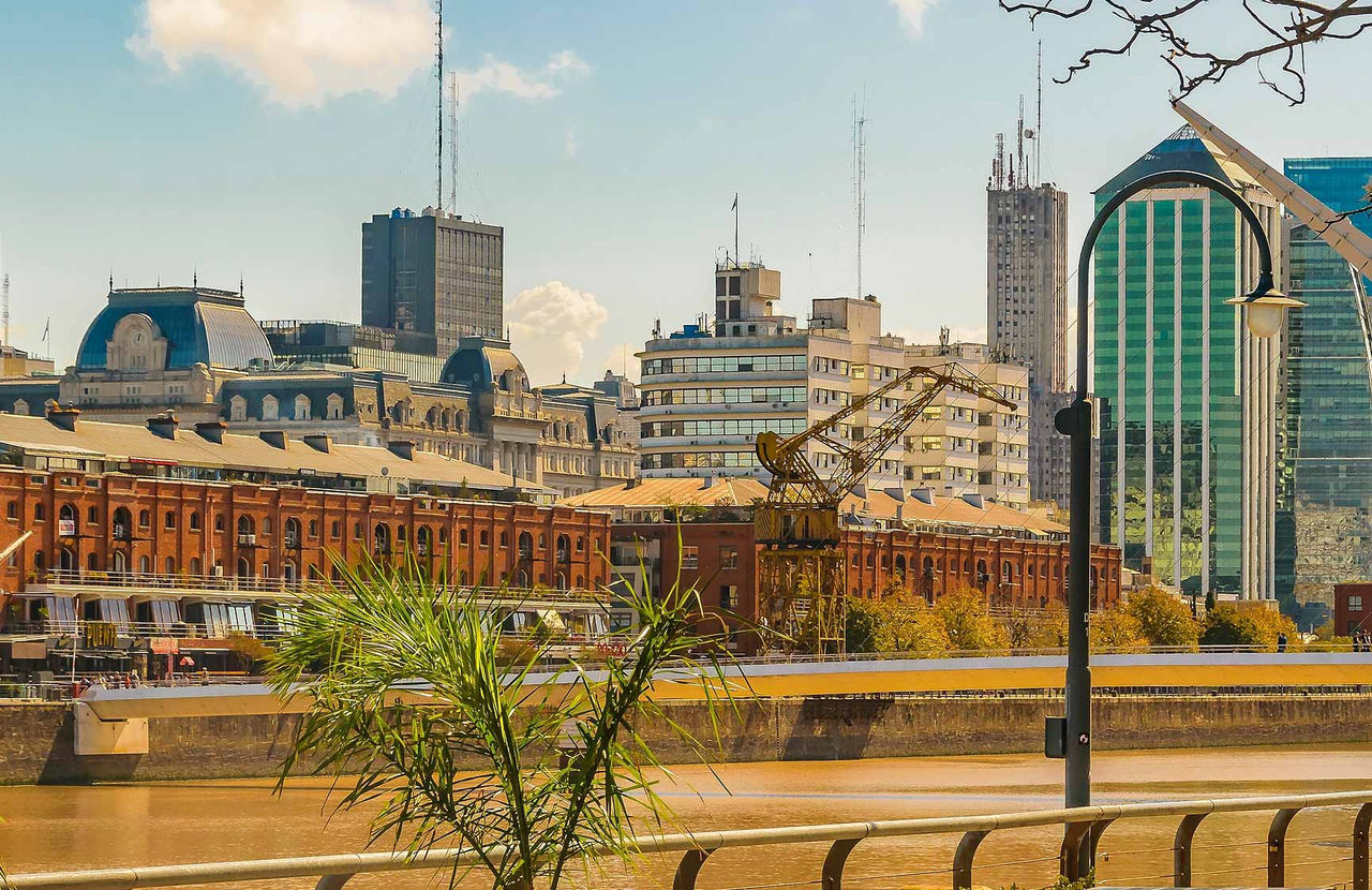Paisagem urbana de Buenos Aires com o bairro portuário de Puerto Madero, com edifícios altos e um rio Prata