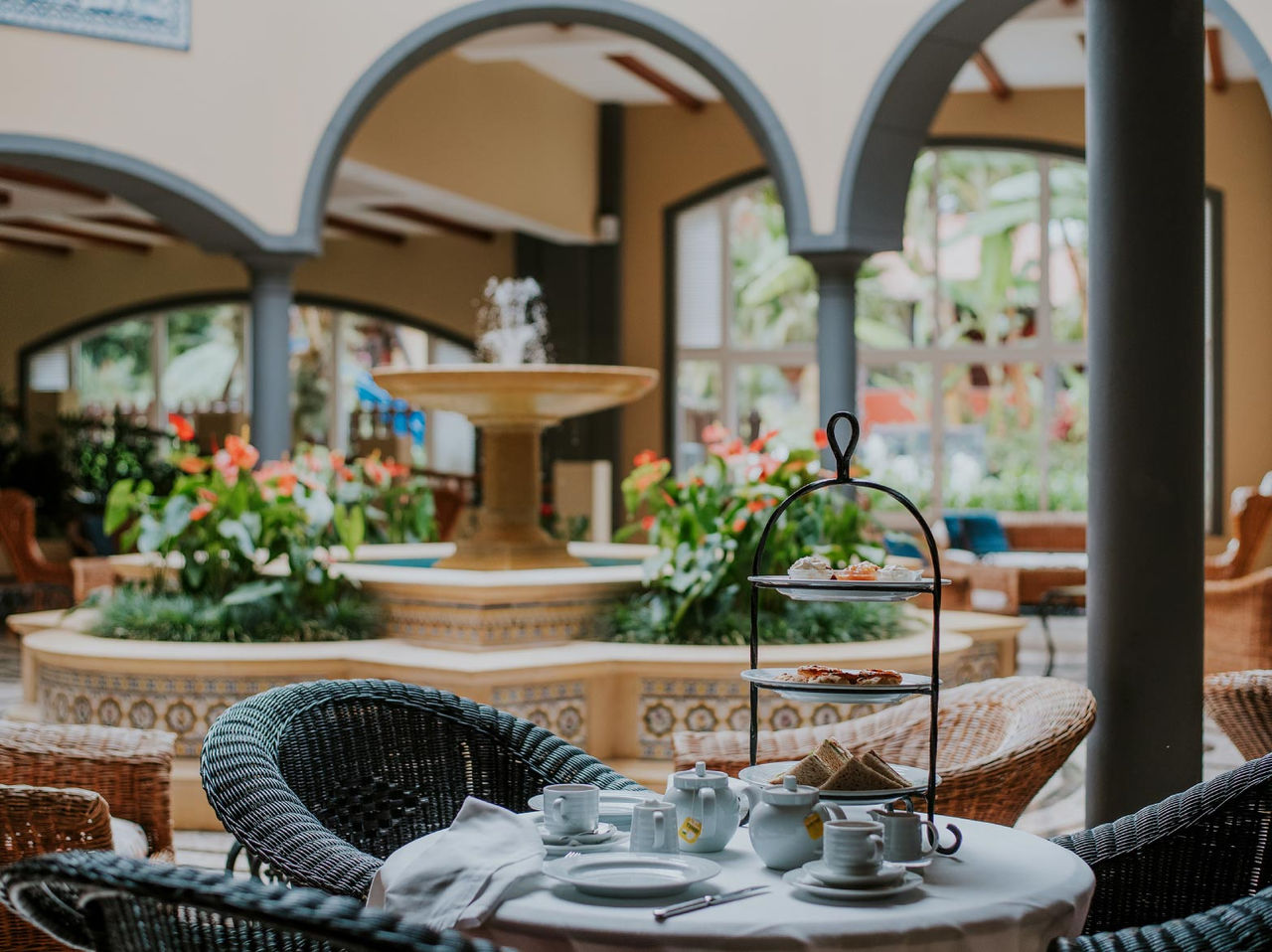 O bar A Fonte, do Hotel de Charme na Madeira tem uma fonte com água e flores e uma mesa com cadeiras