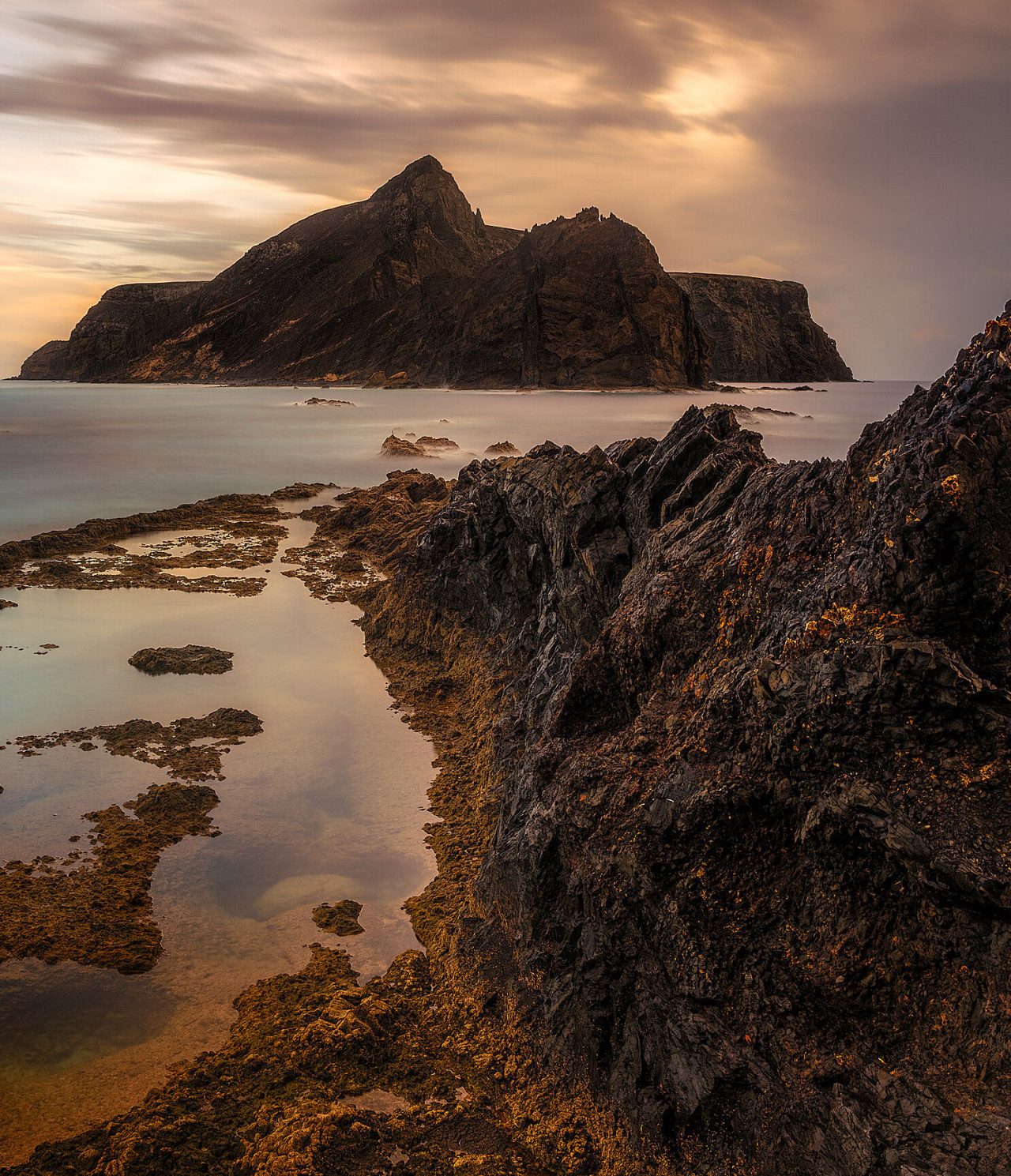 Vista da costa rochosa da ilha do Porto Santo, na Madeira, com uma ilha rochosa ao fundo