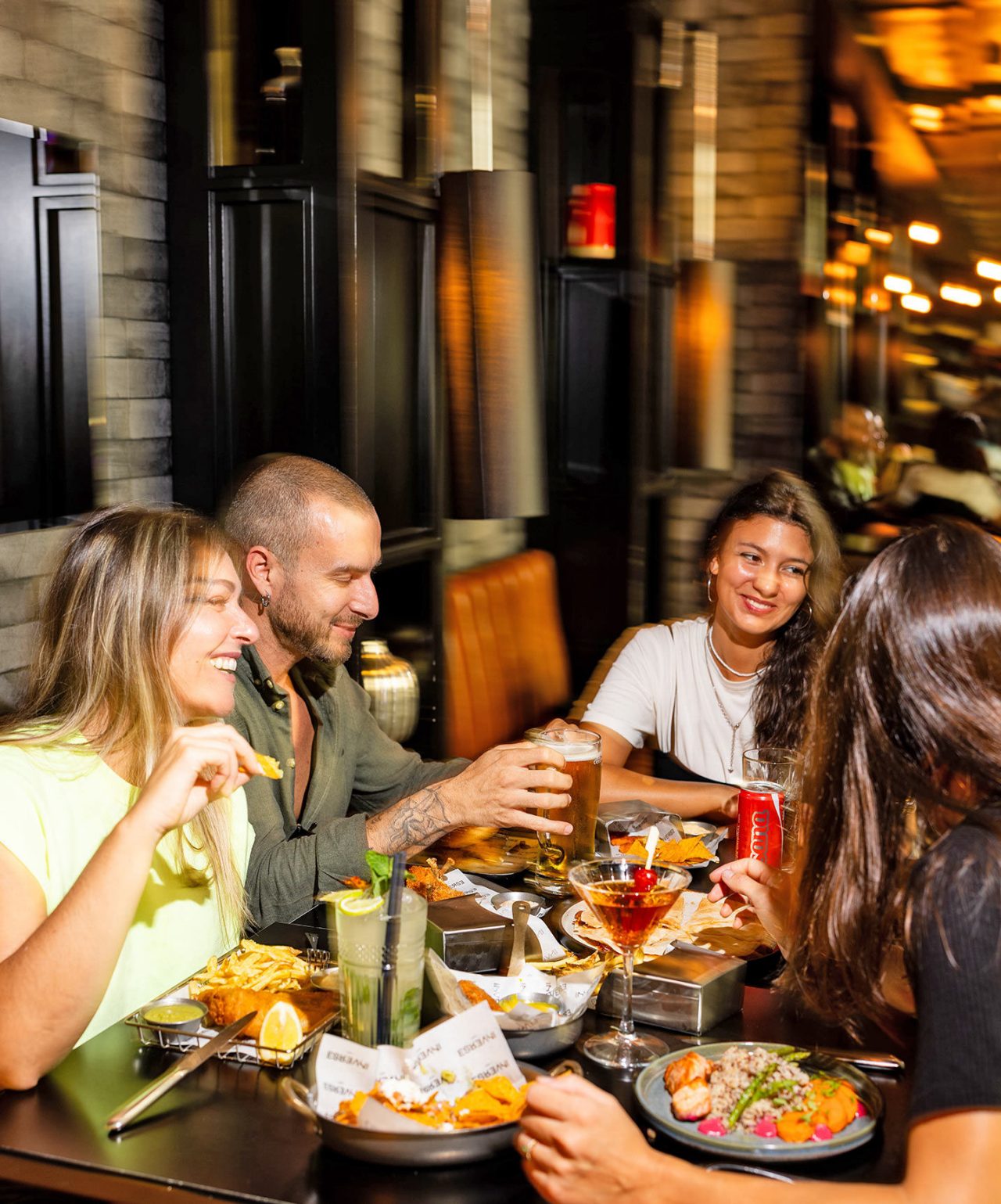 Grupo de amigos desfruta da energia e do ambiente descontraído do sports bar Inverse by CR7 que oferece cocktails e jantar