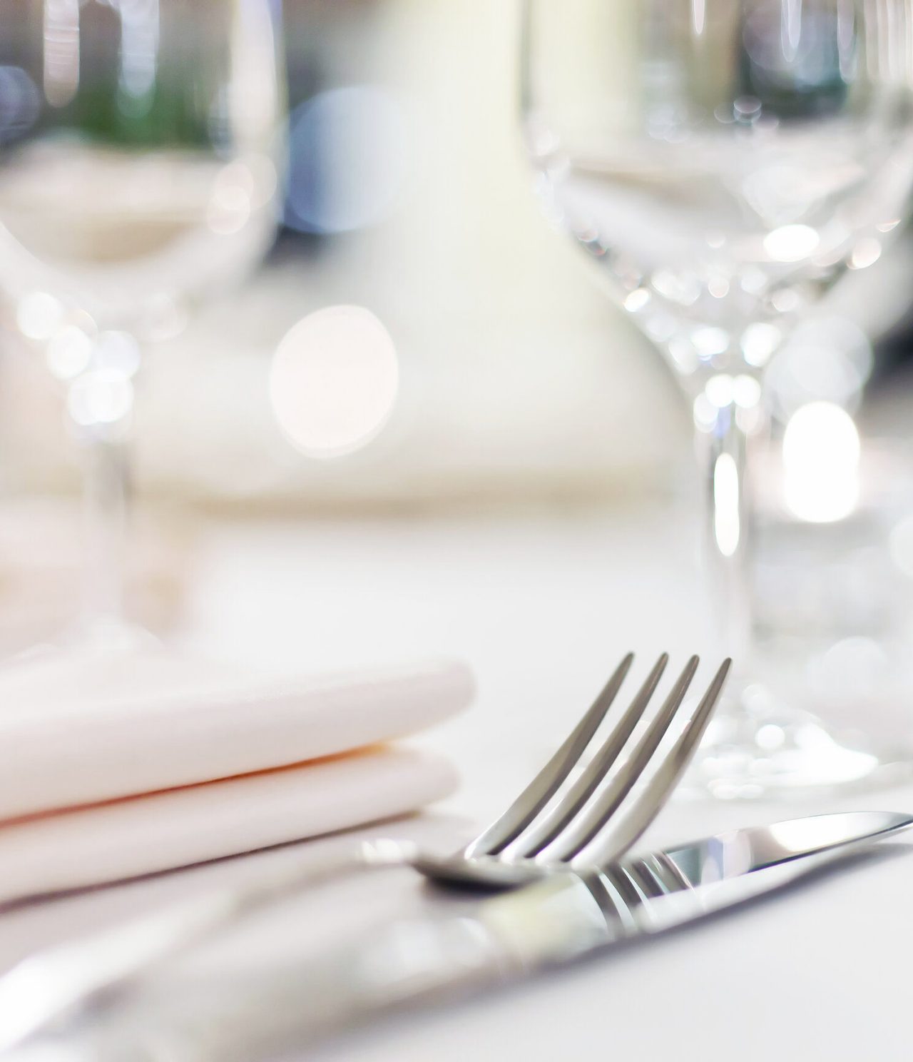 Descubra Hotéis em Tânger apresentando uma mesa elegante com copos, talheres e guardanapos em foco suave