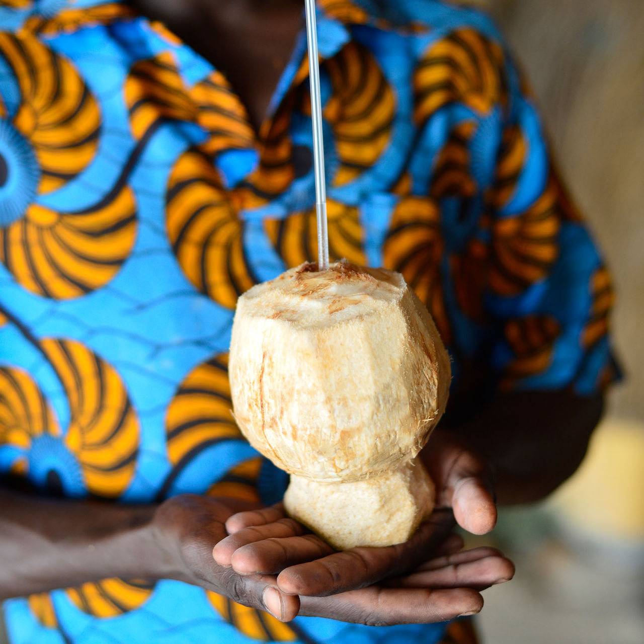 Man in a typical patterned shirt holding a coconut drink, in the coconut