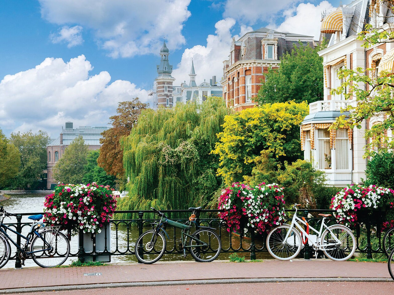 Explore Hotels in Amsterdam featuring canal houses, bicycles and bright flower baskets beside the water