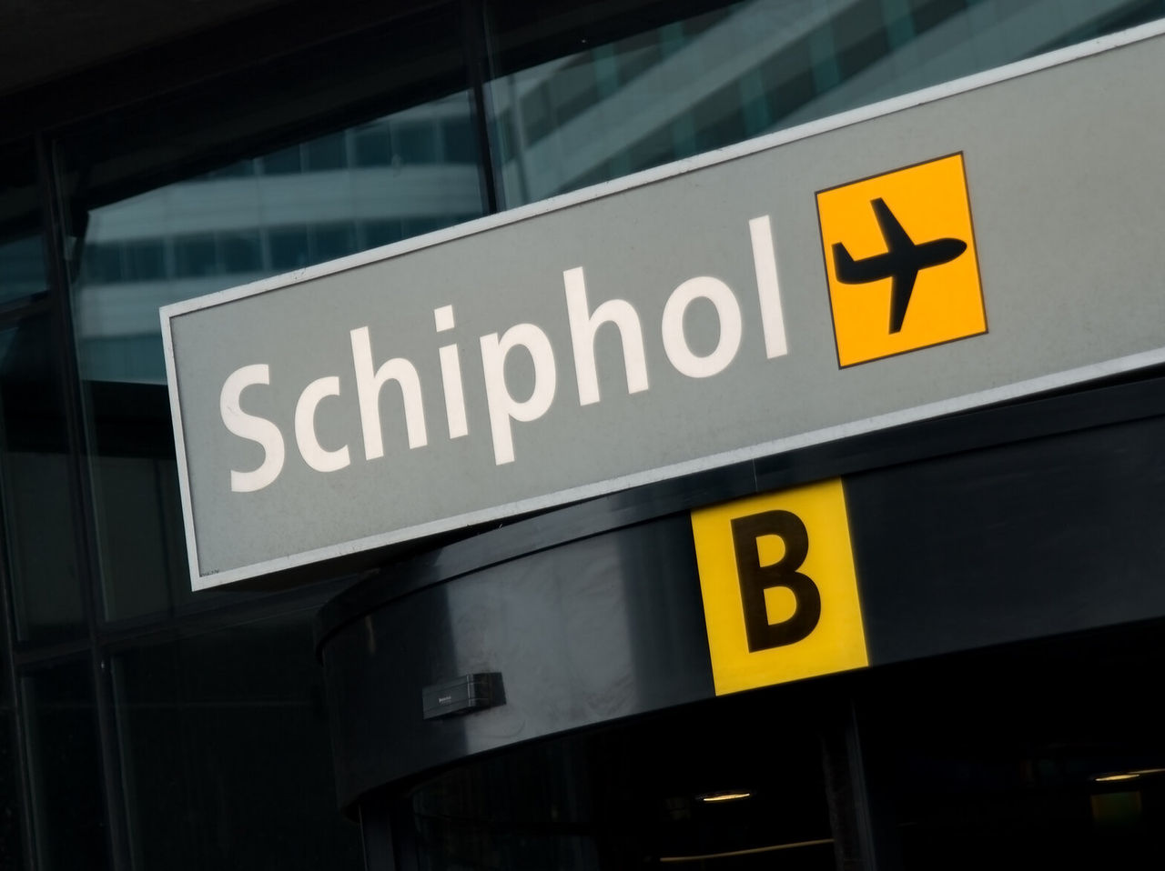 Explore Hotels in Amsterdam featuring a Schiphol airport sign above terminal entrance with yellow symbols