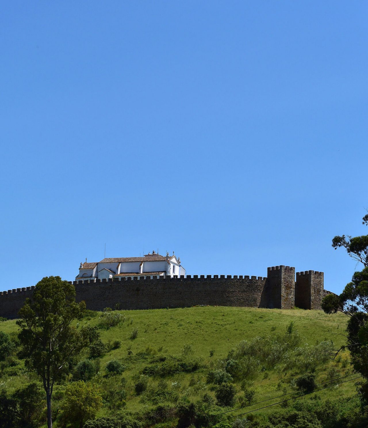 Historic castle on top of a hill in Arraiolos, Alentejo, surrounded by green landscapes and clear blue sky