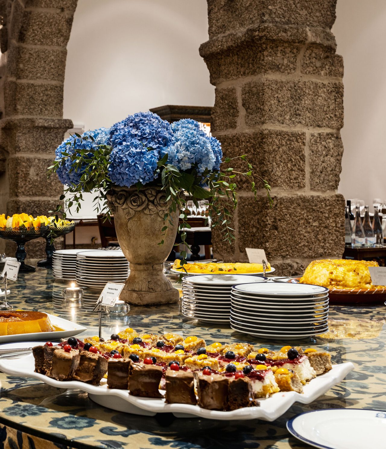 Table decorated with a variety of sweets, from cakes and pies to fresh fruits, in a room with antique furniture