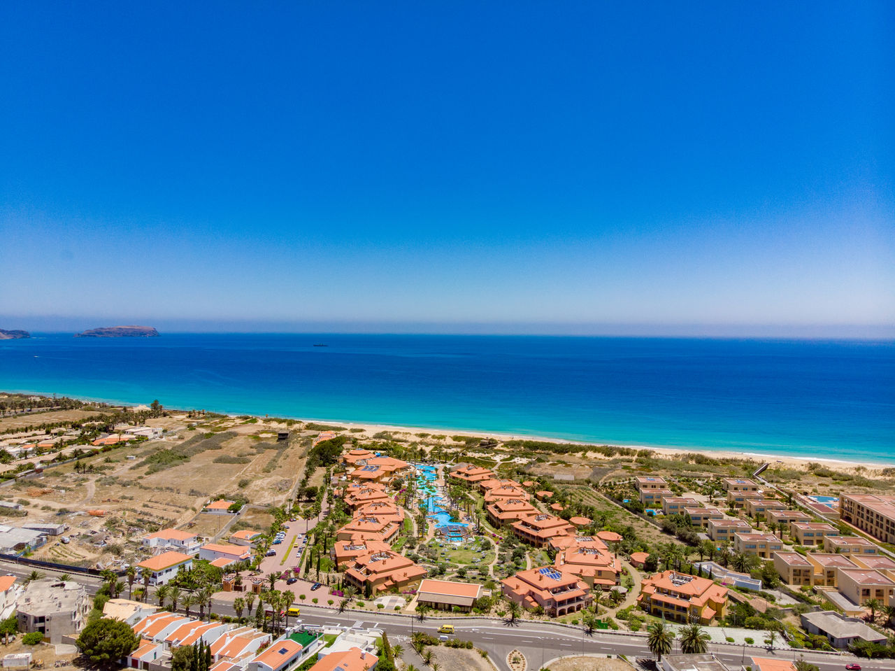 Aerial view of Pestana Porto Santo, with its various buildings and pools, facing a turquoise blue sea
