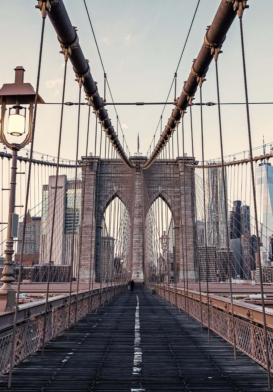 Panoramic view of the Brooklyn Bridge with its steel cables and iron structure under a clear blue sky