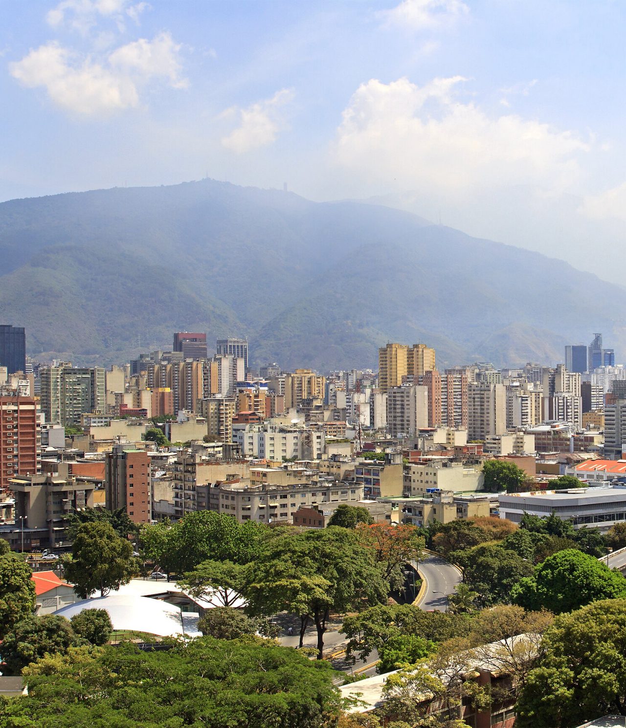 Panoramic aerial view of Caracas, with several tall buildings, some modern constructions, and vegetation