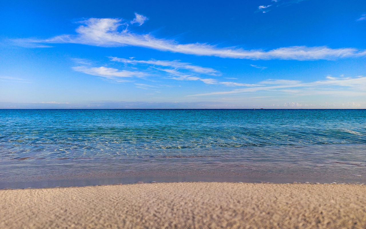Explore Pestana Hotel Group overlooking a calm turquoise sea, pale sandy shore and wispy clouds in blue sky