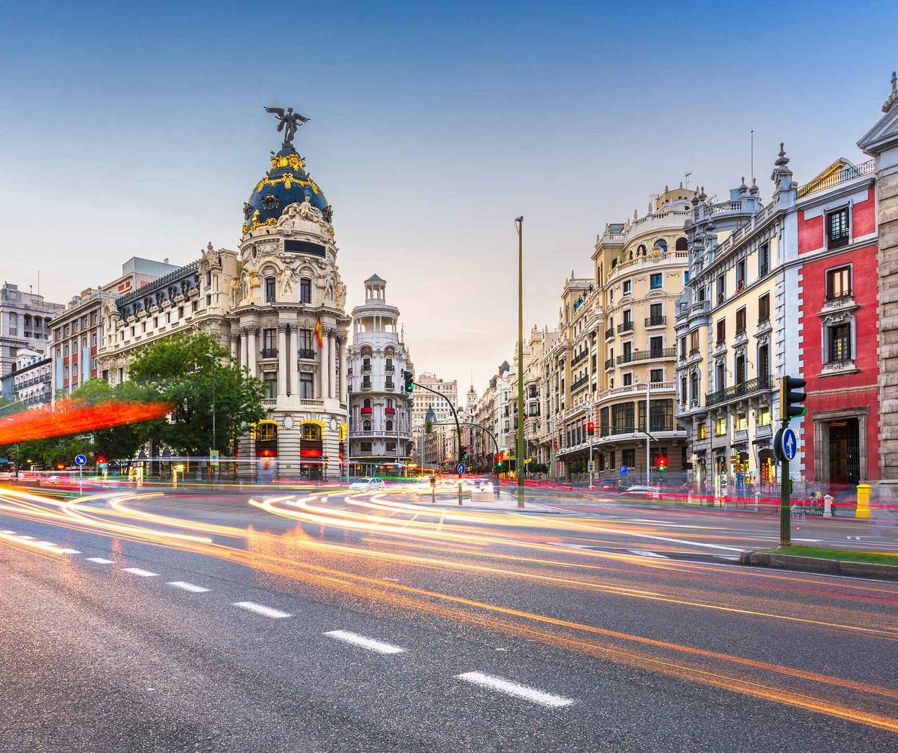 Madrid hotel featuring historic buildings along Gran Vía with evening traffic light trails beneath a clear sky